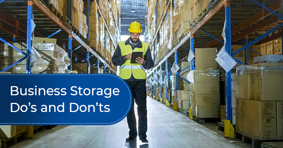 Auditor wearing hard hat walking through a row of storage racks with merchandise.