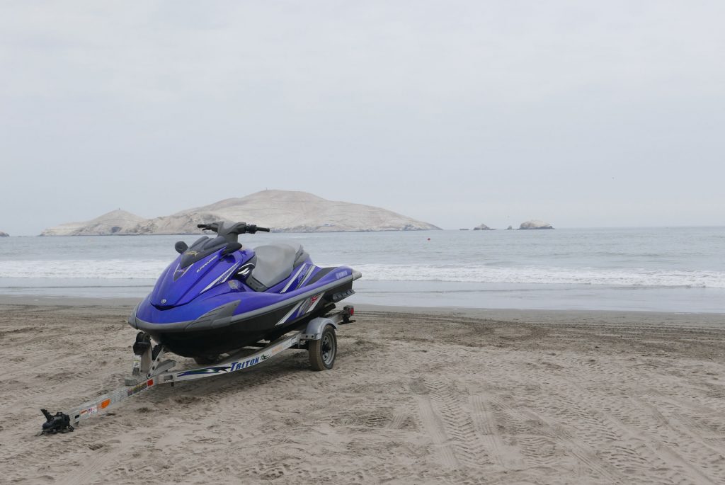 A jetski on a trailer, with a lake in the background on a foggy day.